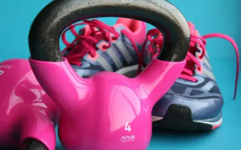 Różowe kettlebelle i buty sportowe marki Adidas gotowe do treningu.