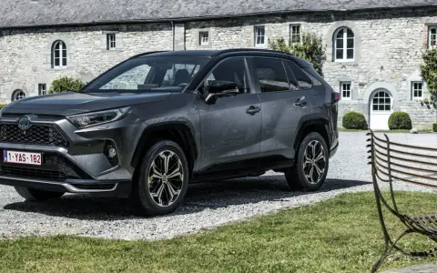 Szary Toyota RAV4 Hybrid przed kamiennym budynkiem. Zastanawiasz się, ile kosztuje Toyota RAV4 Hybrid?