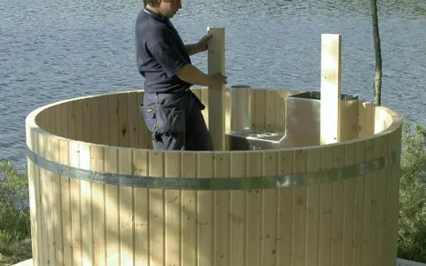 Man bygga badtunna vid sjön. Träet är nytt och redo för montering.