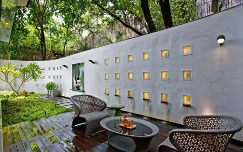 Un oasis moderno para decorar pared terraza pequeña. Muebles de mimbre, plantas exuberantes y cascadas de agua crean un ambiente sereno.