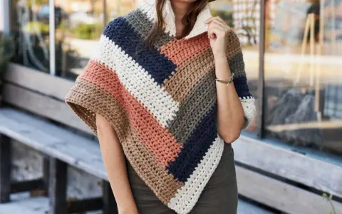 Mujer con un poncho de ganchillo a rayas en tonos tierra, azul marino y blanco. El patrón poncho es ideal para el otoño.