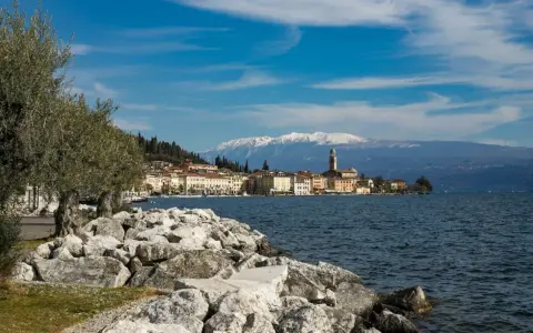 Vista di un borgo sul lago, con montagne innevate sullo sfondo. Perfetto per sapere dove andare 2 giorni in vacanza nord Italia.