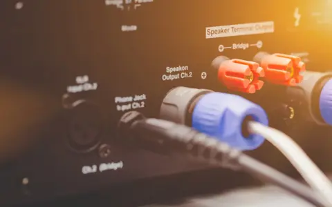 Złącza Speakon i zaciski głośnikowe na wzmacniaczu, pokazujące różne **cable types** do podłączenia sprzętu audio.