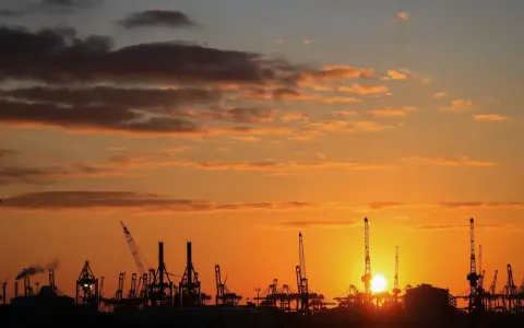 Silhouetten von Kränen im Hamburger Hafen bei Sonnenuntergang. Perfekt für die Pfingstferien in Hamburg.