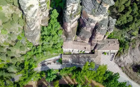 Vista aérea del **barranco de la Hoz, Guadalajara**, con edificios integrados en las rocas y vegetación exuberante.