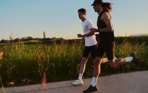 Zwei Männer laufen auf einem Feldweg, die Sonne scheint. Sie wollen schneller laufen und genießen die Abendstimmung.