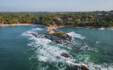 Malownicze wybrzeże, gdzie leży Sri Lanka. Tropikalna roślinność, plaże i skaliste wysepki w turkusowej wodzie.