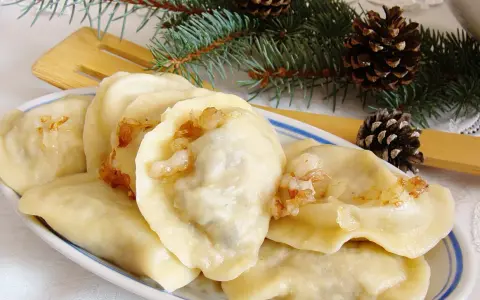 Pyszne pierogi z mięsem i kapustą, ozdobione gałązkami świerku i szyszkami, wyglądają jak świąteczny przysmak.
