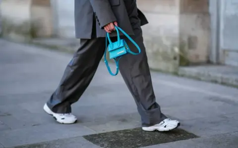 Elegancki damski garnitur w połączeniu z białymi sneakersami i turkusową torebką.