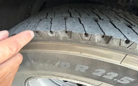 Dito un dito indica pneumatici con lesioni sui fianchi, mostrando crepe e usura preoccupanti.