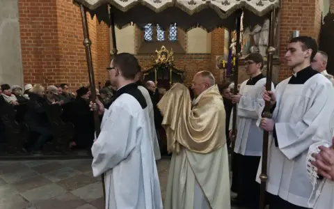 Uroczysta procesja w kościele, kapłan niesie monstrancję okrytą złotym welonem. To symboliczna rezurekcja.