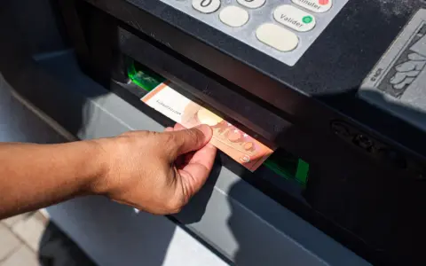 Mano sacando un billete de 50 euros de un cajero automático. La imagen muestra la acción de retirar dinero, lo que nos hace pensar en cuanto dinero se puede sacar del cajero.