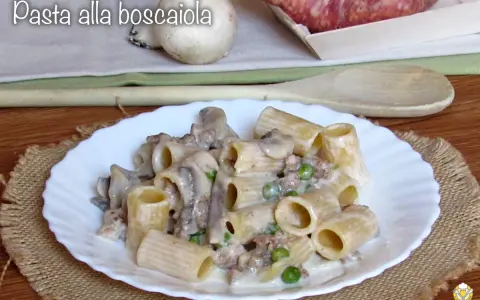 Piatto di pasta alla boscaiola con funghi, piselli e salsiccia, servita su un piatto bianco con una tovaglietta di juta.
