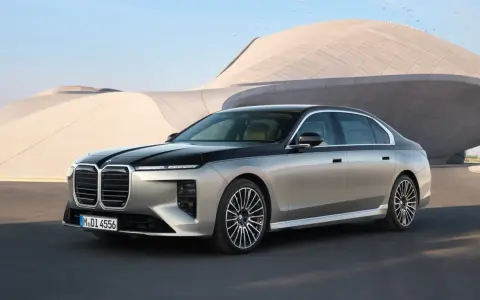Elegancki BMW 740d w dwukolorowym malowaniu, zaparkowany przed nowoczesnym budynkiem.