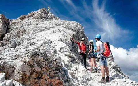 Bergsteiger am Gipfel der Zugspitze ohne Klettersteig. Ein Führer erklärt den Weg.
