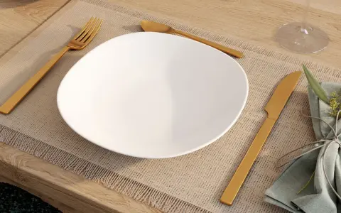 Une assiette blanche est dressée sur un set de table, avec la position des couverts à la française : fourchette à gauche, couteau à droite.