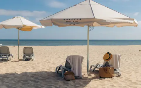 Leżaki i parasole na piaszczystej plaży nad morzem.