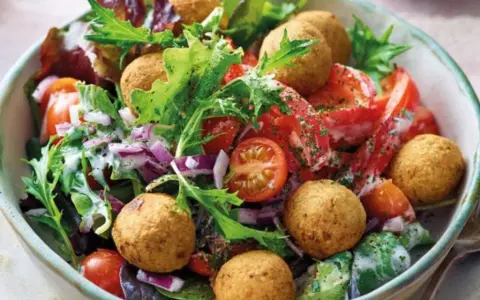 Bunter Salat mit Tomaten, Zwiebeln und Falafelbällchen. Ein schnelles gesundes Essen, das gut aussieht und schmeckt.