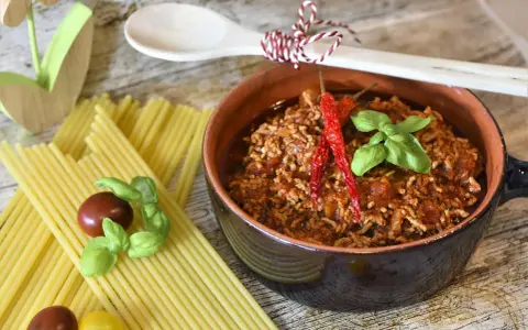 Un invitante ragù, pronto per la pasta, con peperoncini e basilico. La ricetta perfetta per un pranzo gustoso.