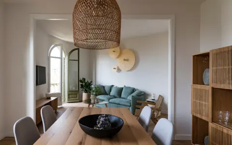 Comedor y sala minimalista para espacios pequeños. Mesa de madera, sillas grises, sofá verde menta y estantería de roble.