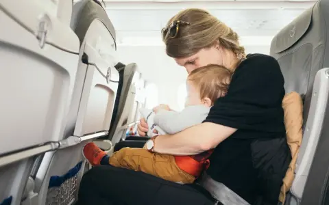 Mama tuli do samolotu z dzieckiem. Siedzą obok siebie, a dziecko bawi się zabawką.