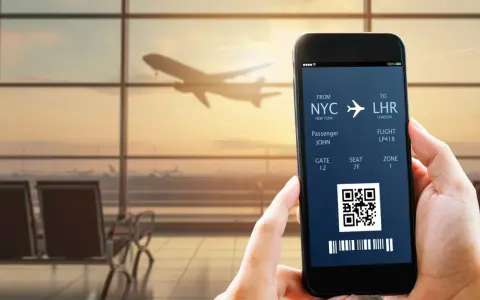 Bilet lotniczy na telefonie: lot z NYC do LHR, pasażer John, bramka 12. IATA co to? To kod lotniska.