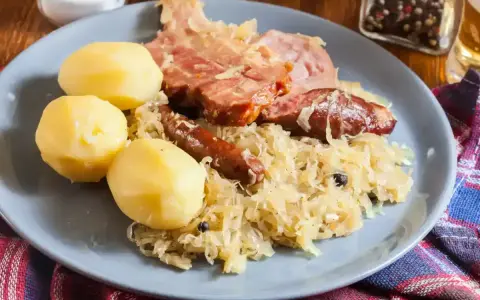 Une assiette de choucroute garnie, avec pommes de terre, saucisses et viande fumée. Un plat qui raconte une histoire culinaire.