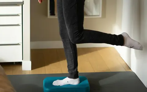 Personne effectuant des exercices de renforcement de la cheville sur un step bleu, idéal pour la rééducation après une entorse.