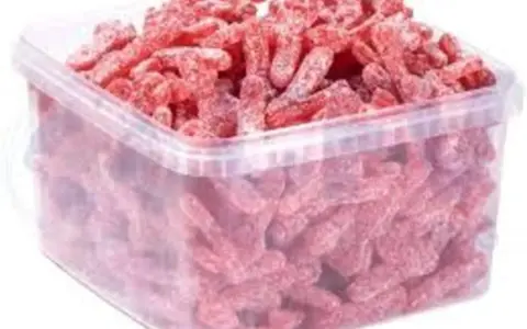 Un cubo transparente lleno de gominolas rojas con forma de gusano, cubiertas de azúcar. ¡Parecen la chuche más ácida del mundo!