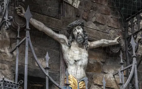 Kreuzigungsgruppe mit Jesus, der die Frage aufwirft, wie alt war Jesus als er starb. Davor ein schmiedeeiserner Zaun.