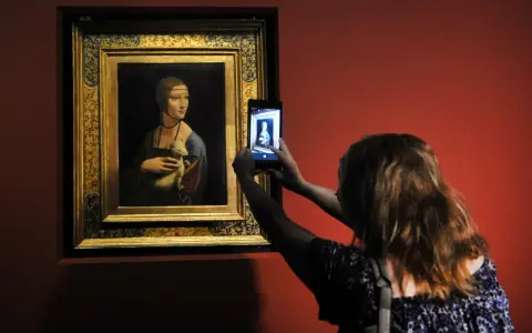 Dama z łasiczką w muzeum, gdzie jest? Kobieta robi zdjęcie słynnego obrazu telefonem.