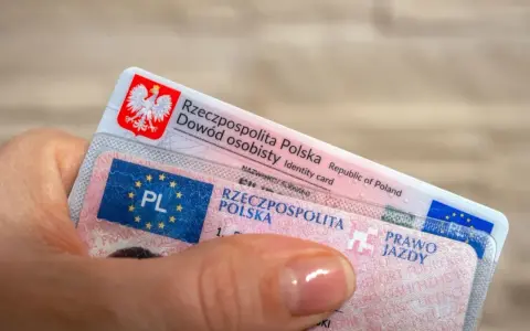 Dłoń trzyma polski dowód osobisty i prawo jazdy. Dokumenty te mogą być przydatne, gdy planujesz podróż do USA i chcesz mieć pewność, że Twoje polskie prawo jazdy jest uznawane.
