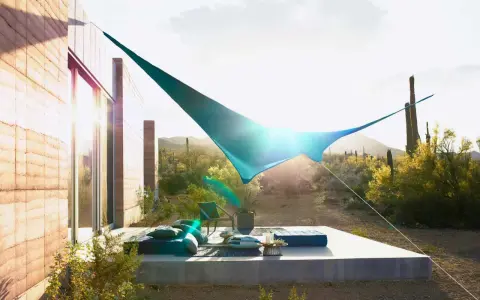 Ideas de sombra para terraza desértica: una vela azul crea un oasis fresco sobre cojines y un sillón.