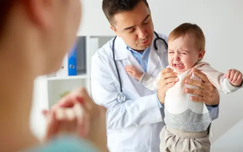 Lekarz uspokaja płaczące dziecko, które przechodzi skok rozwojowy 4 latka. Mama wspiera malucha.
