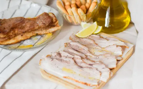 Chicharrón de Cádiz, lonchas de panceta crujiente, palitos de pan y aceite de oliva.
