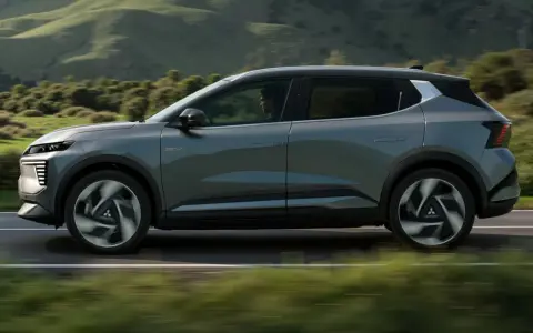 Nowy, elektryczny Mitsubishi Eclipse Cross sunie po malowniczej drodze, otoczony zielonymi wzgórzami.