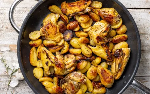 Pollo con patate in padella, dorato e saporito, con erbe aromatiche. Un piatto rustico e invitante.