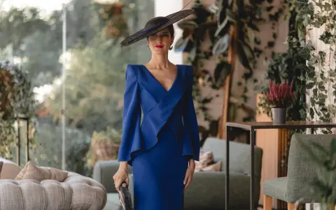 Elegante mujer con vestido azul klein y sombrero, ideal para saber como combinar un vestido azul klein para una boda.