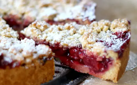 Ein saftiger Kirschstreuselkuchen, bestäubt mit Puderzucker, wartet darauf, genossen zu werden.
