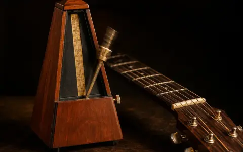 Un métronome en bois et une guitare acoustique, prêts pour la répétition. Le métronome bat la mesure, le temps de **half time** est en cours.