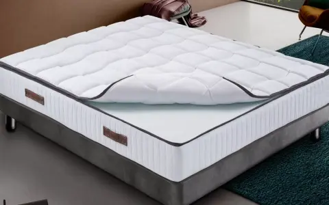 Un matelas king size mémoire de forme, blanc matelassé, sur un sommier gris. Confort garanti pour des nuits paisibles.