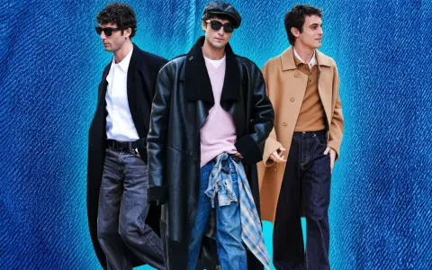 Tre uomini con un outfit elegante con jeans. Uno indossa un cappotto nero, camicia bianca e jeans grigi. Un altro un cappotto in pelle nero, maglione rosa e jeans blu. Il terzo un cappotto cammello, maglione marrone e jeans scuri.