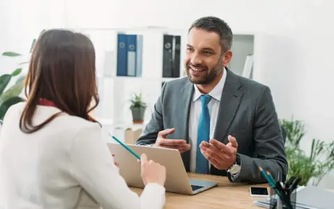 Un hombre sonriente, que parece ser un asesor energético, explica algo a una mujer en una oficina.