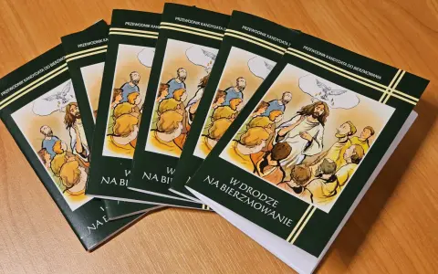 Kilka zielonych książek z ilustracją Jezusa i gołębicy na drewnianym stole.