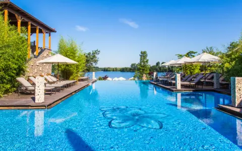 Entspannung pur im Solebad NRW: Ein luxuriöser Pool mit Blick auf den See, umgeben von Bambus und Liegestühlen.