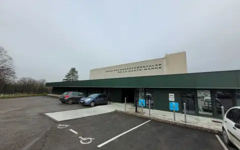 Devant les archives départementales 52, deux voitures sont garées près de l'entrée. Le bâtiment porte l'inscription "ARCHIVES DEPARTEMENTALES DE LA HAUTE-MARNE".