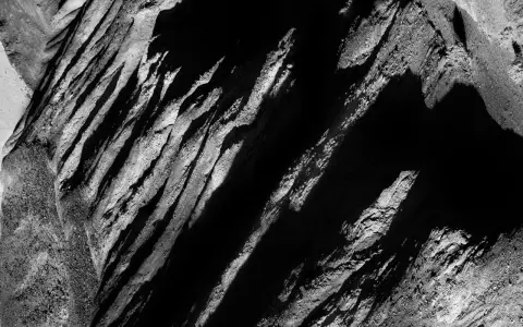 Abstract black and white landscape, reminiscent of Aaron Siskind photos, with dramatic shadows and textured rock formations.