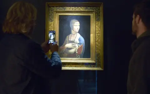 Dama z gronostajem Leonarda da Vinci, uwieczniona na zdjęciu przez turystkę. Obok obrazu stoi mężczyzna.