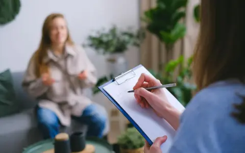Psychologia kliniczna w praktyce: terapeuta notuje objawy pacjentki, która opowiada o swoich problemach.