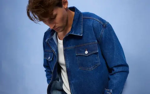 Mężczyzna w dżinsowej kurtce, idealnej do stworzenia uniwersalnej szafy kapsułowej. Klasyczny krój i niebieski denim.